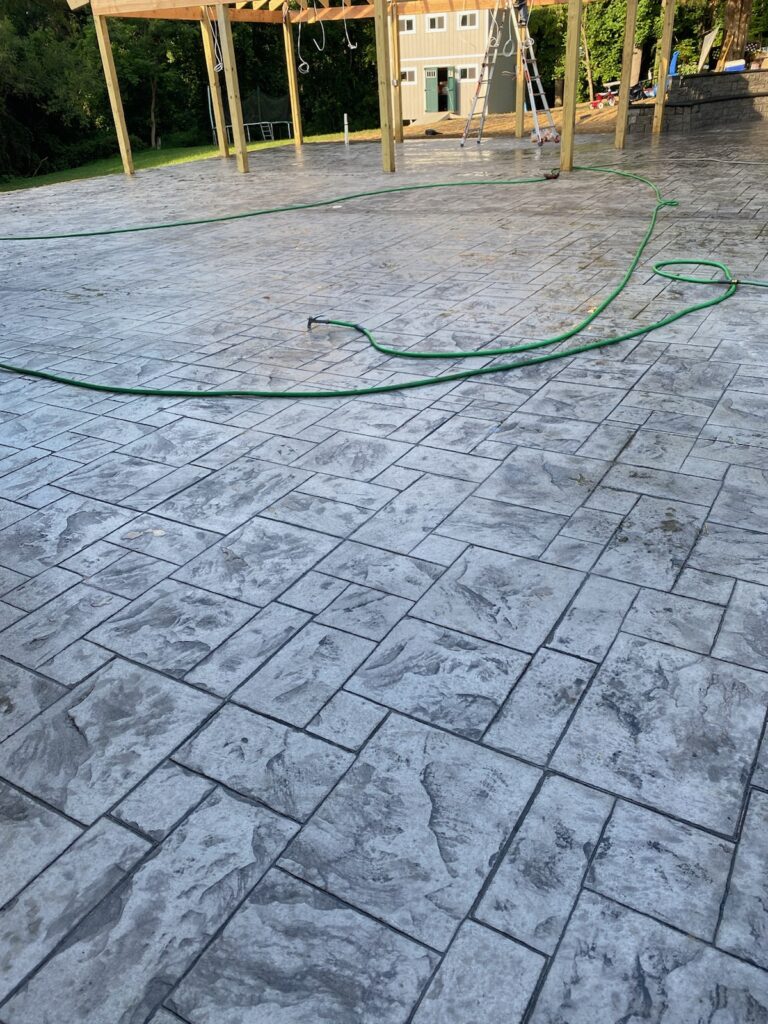 A textured concrete surface, possibly a patio or driveway, with a subtle pattern resembling natural stone or pavers.